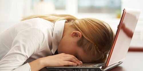 woman laying her head on the keyboard of her laptop