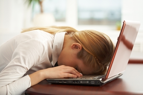 woman laying her head on the keyboard of her laptop