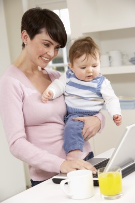 woman working from home as she holds her baby