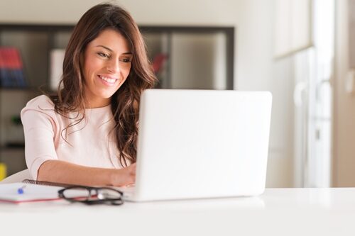 Woman smiling as she works on her laptop in a bright office