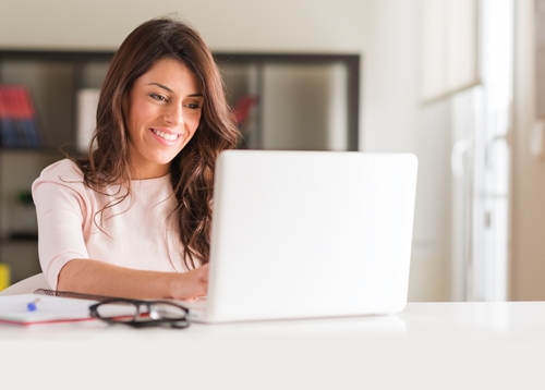 Woman smiling as she works on her laptop in a bright office