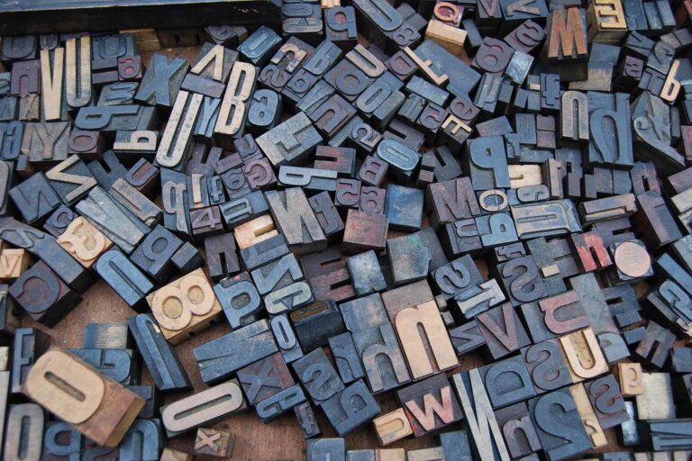 Wooden blocks with letters and numbers all laying in a jumble on the floor.