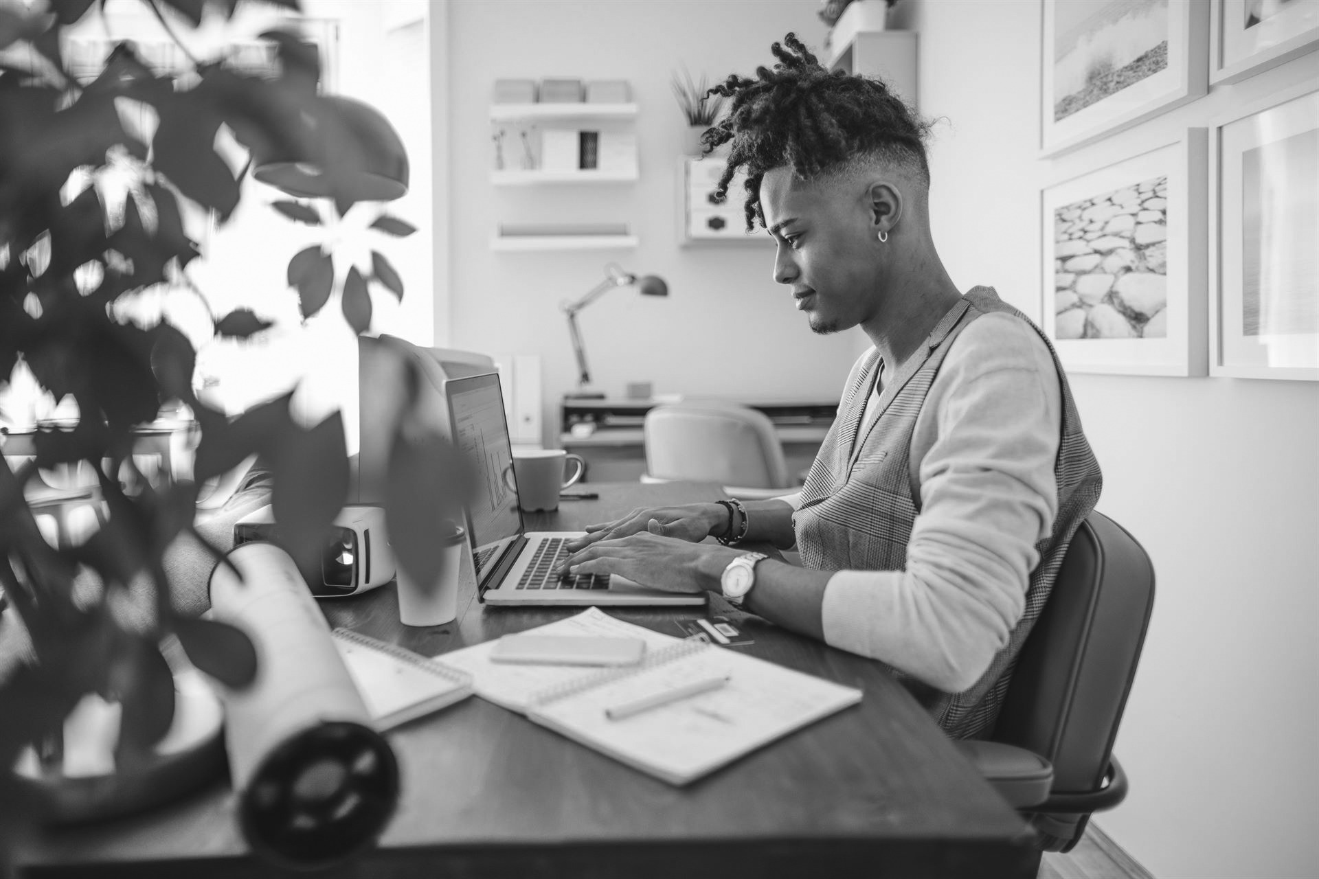 Side view of a young man working at his desk on his laptop.