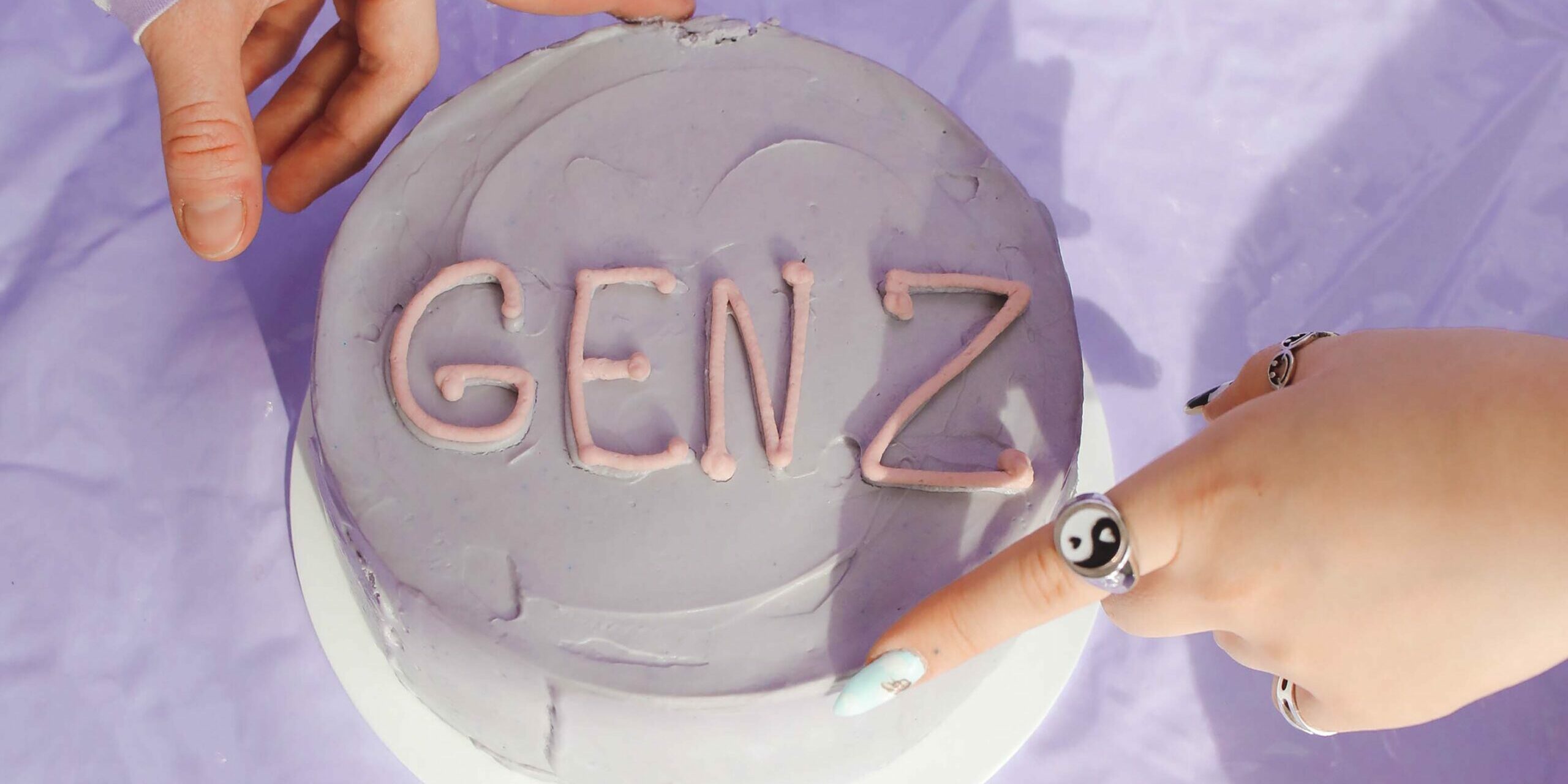 hands on light purple cake that says "gen z" - gen z in the workplace