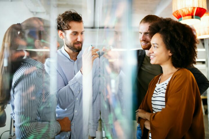 reasons embedded teams outperform traditional outsourcing group of professionals around a clear white board