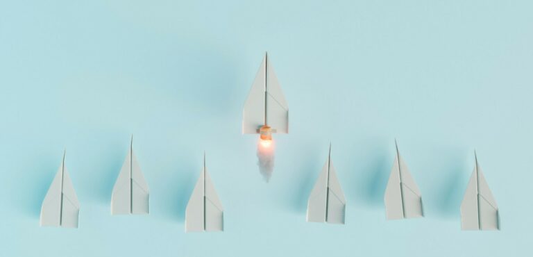 paper airplanes in a line with one taking off to symbolize leadership