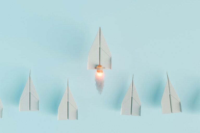 paper airplanes in a line with one taking off to symbolize leadership