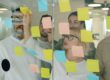 Marketing team brainstorming with sticky notes to design workflow and team structure