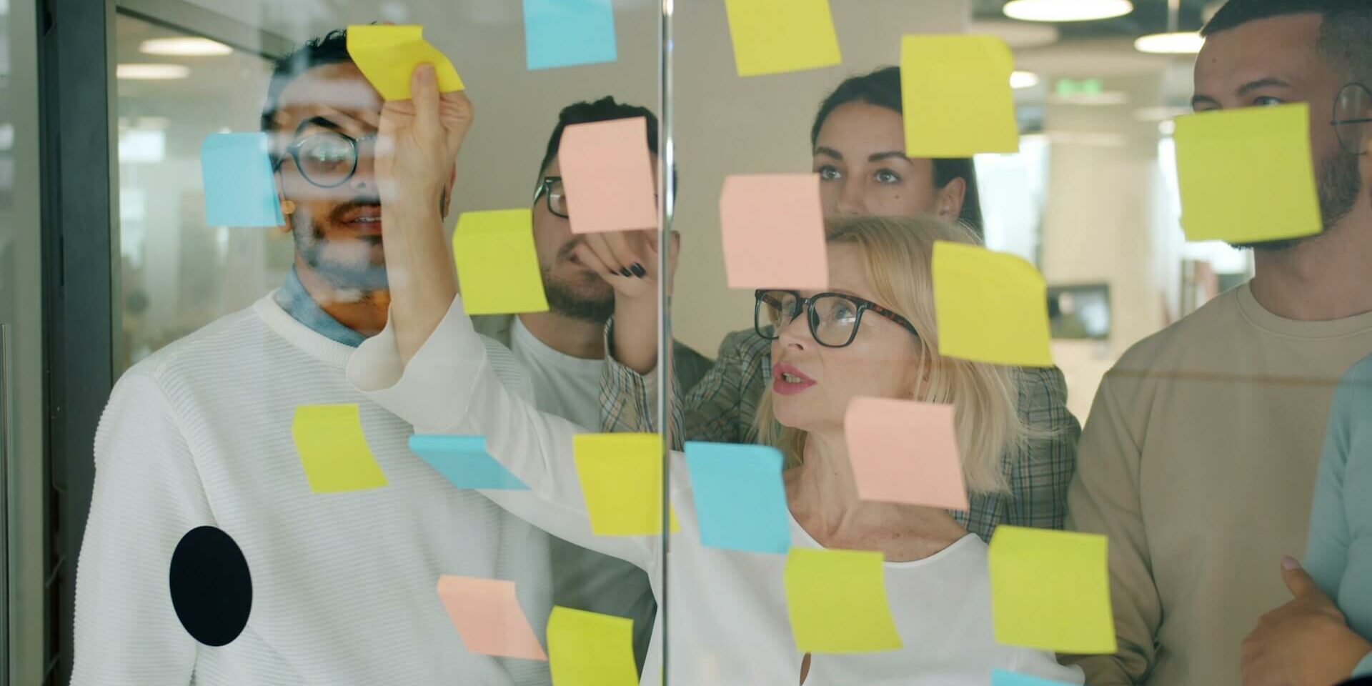 how to structure an AI marketing team Marketing team brainstorming with sticky notes to design workflow and team structure