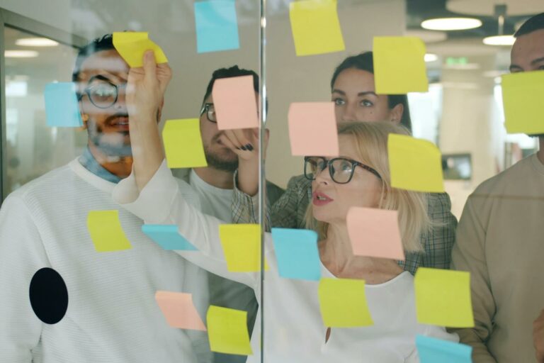 how to structure an AI marketing team Marketing team brainstorming with sticky notes to design workflow and team structure